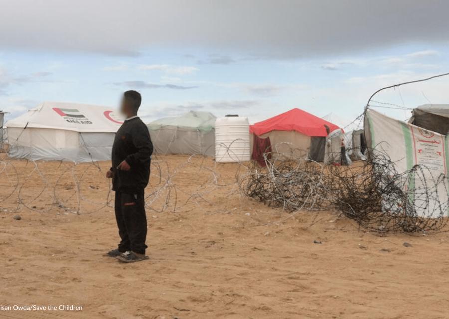 bambino a Gaza di fronte filo spinato e campo per sfollati