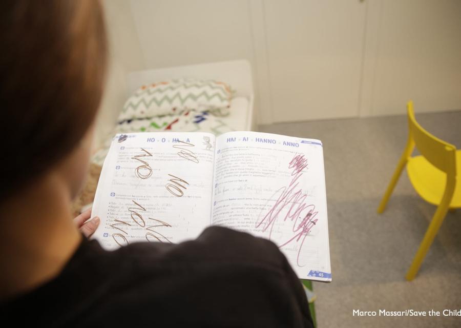 Disegni su un quaderno e bambina di spalle che li guarda