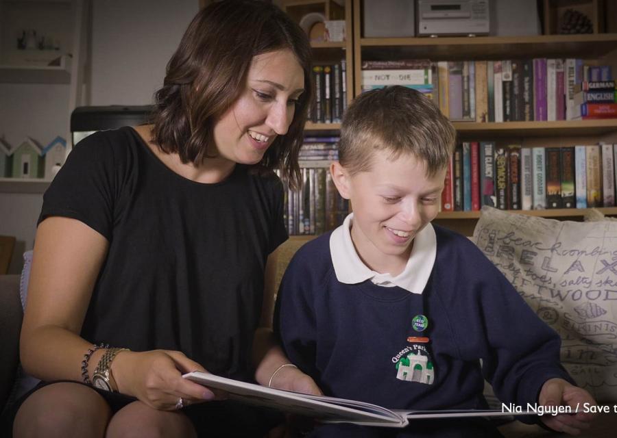 Una mamma e suo figlio leggono insieme un libro seduto sul divano di casa