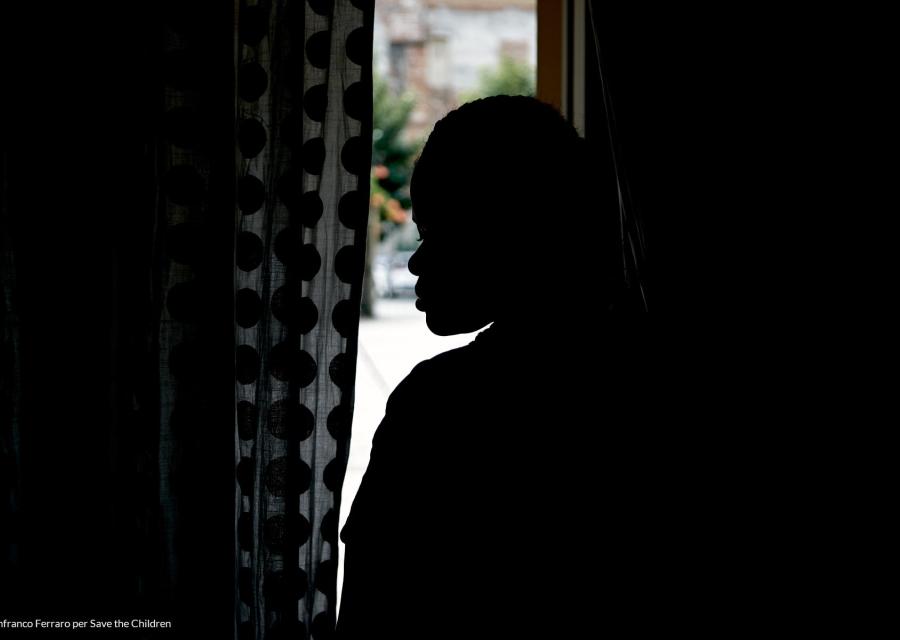 Profilo di una donna in controluce fronte tenda e finestra