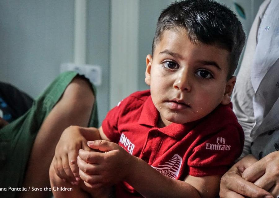 Bambino seduto, con indosso una t-shirt rossa