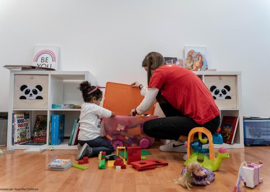 Un bambino svolge attività psicomotorie con il sostegno di una operatrice di Save the Children