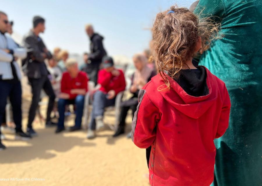 bambina a Rafah di spalle di fronte ad altre persone sfocate