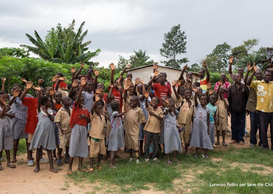 Comunita del cacao Ivoriana di bambini e adulti posa per una foto di gruppo davanti ad alcune case del villaggio