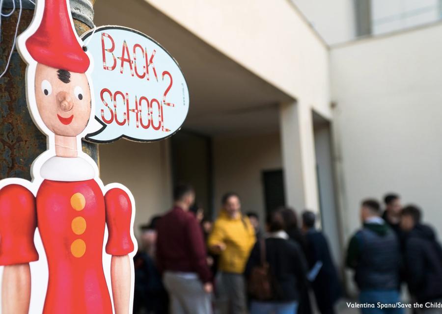 Cartello di pinocchio con fumetto della scritta "back to school" e persone in sfondo