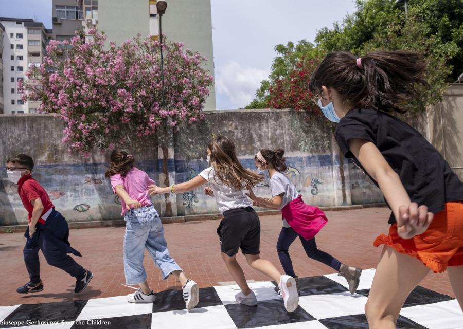 4 ragazze e un ragazzo che giocano a correre in un cortile