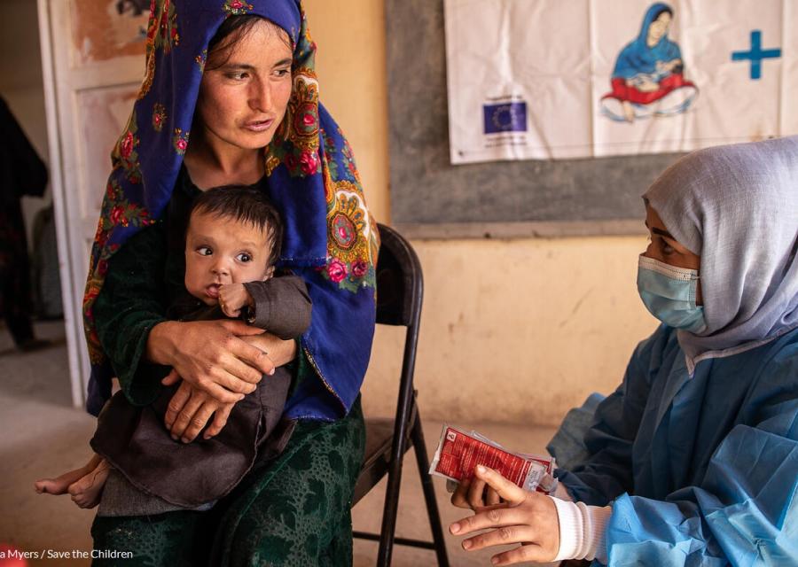 bambina in braccio a madre afghana mentre l'operatrice le offre assistenza sanitaria