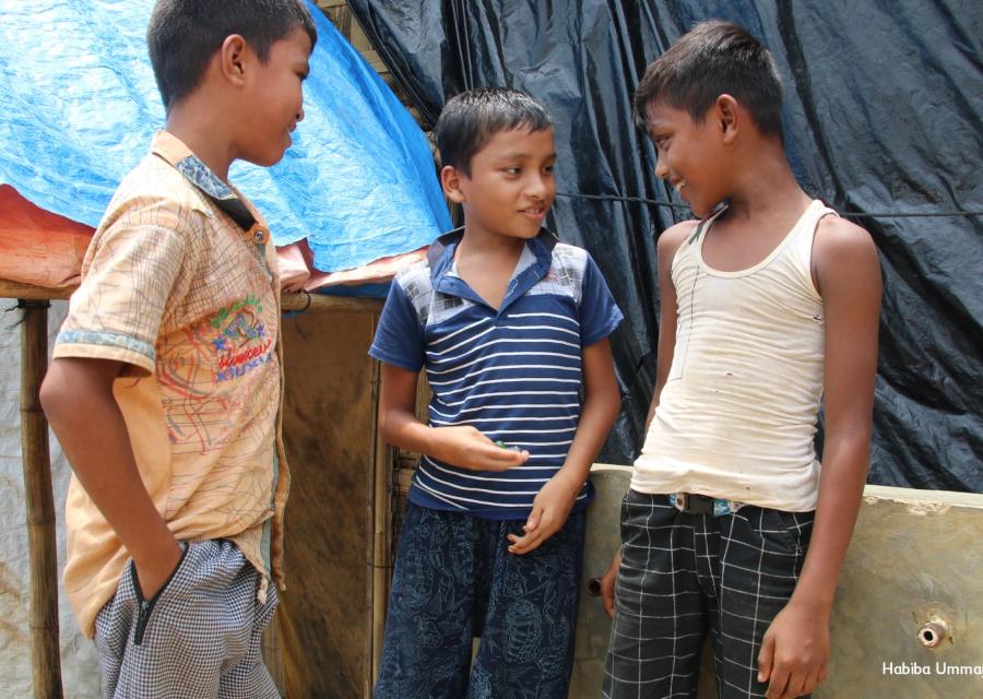 Tre bambini rohingya uno a fianco all altro in piedi parlano tra loro