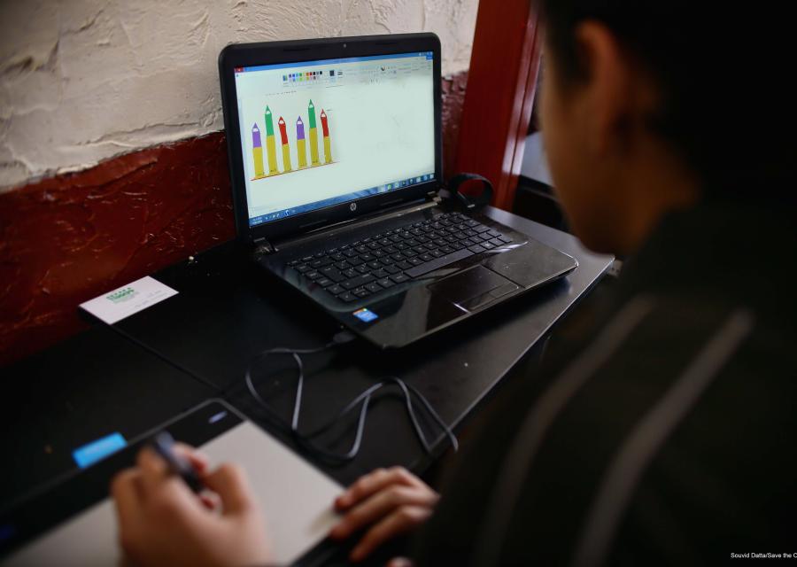 Bambino di spalle scrive vicino a un computer portatile sulla scrivania