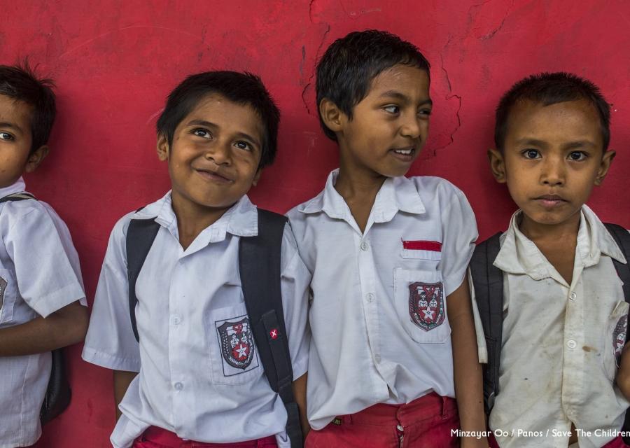 Quattro bambini in divisa scolastica appoggiati al muro