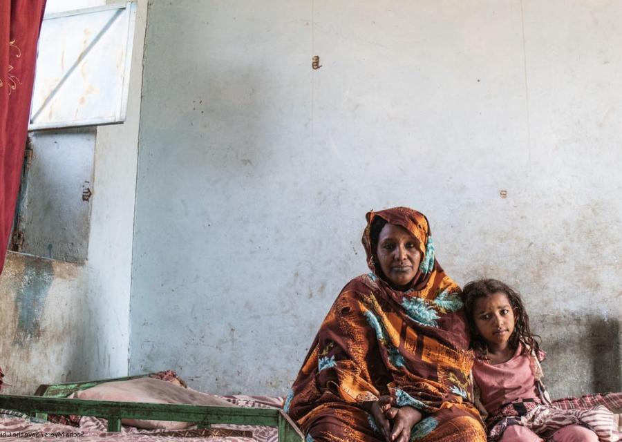 bambina seduta sul letto accanto alla madre in Sudan