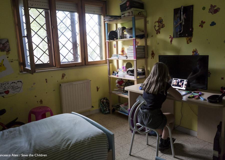 ragazza nella sua camera da letto alla scrivania mentre segue le lezioni in didattica a distanza