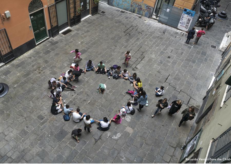 Foto dall'alto di bambini seduti in cerchio in un cortile scolastico