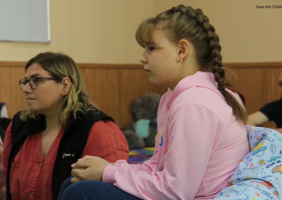 Una bambina di 10 anni con la treccia bionda e una signora a fianco a lei sono di profilo e guardano qualcosa davanti a loro.
