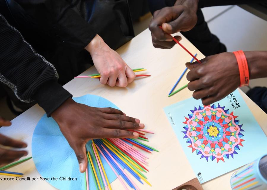 mani di ragazzini prese dall alto colorano un disegno appoggiato sul tavolo