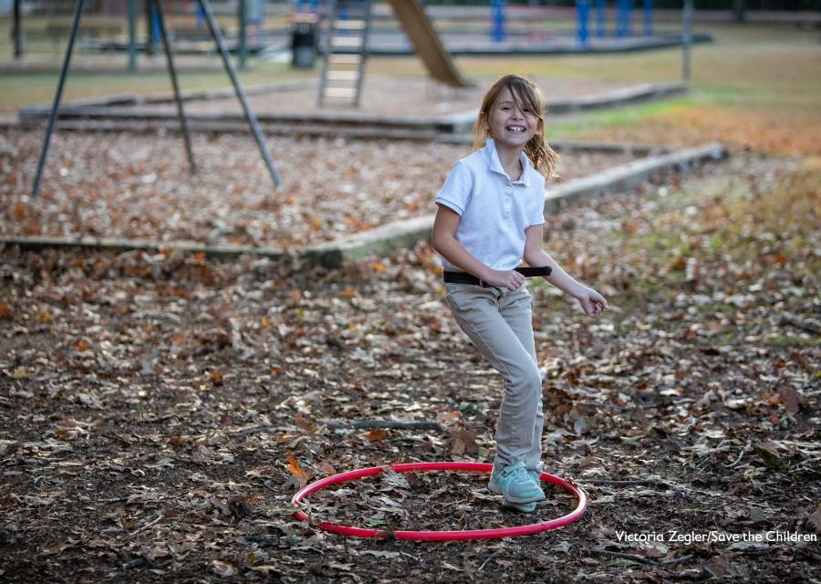 Bambina bionda gioca in un parco con cerchio