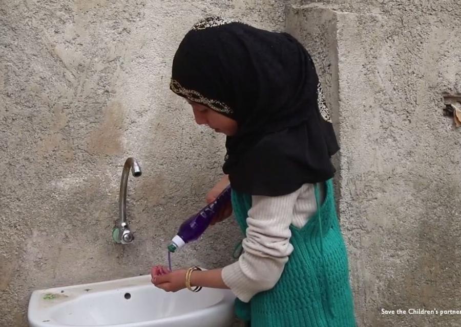 Bambina siriana di profilo vera il sapone sulle mani prima di lavarle al lavandino di fronte a lei.