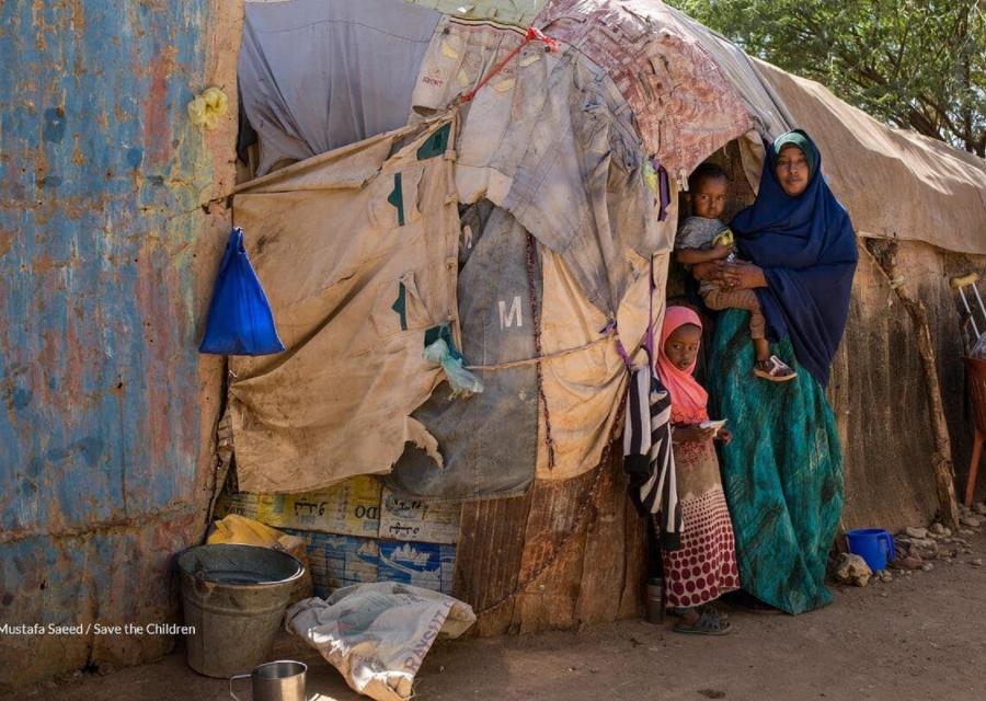 Madre con in braccio il proprio bambino e accanto alla figlia davanti alla loro capanna in Somalia