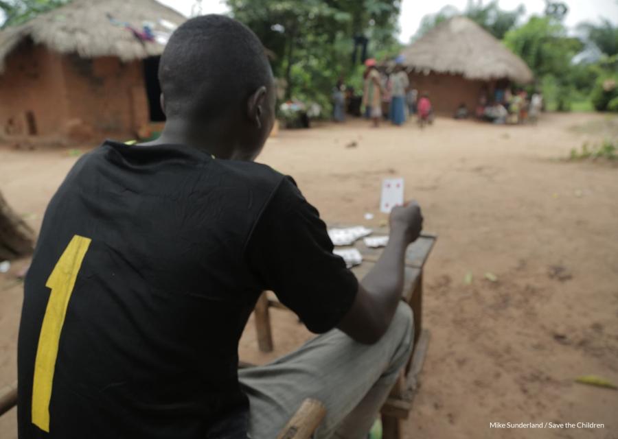 un ragazzo congolese seduto di spalle gioca a carte
