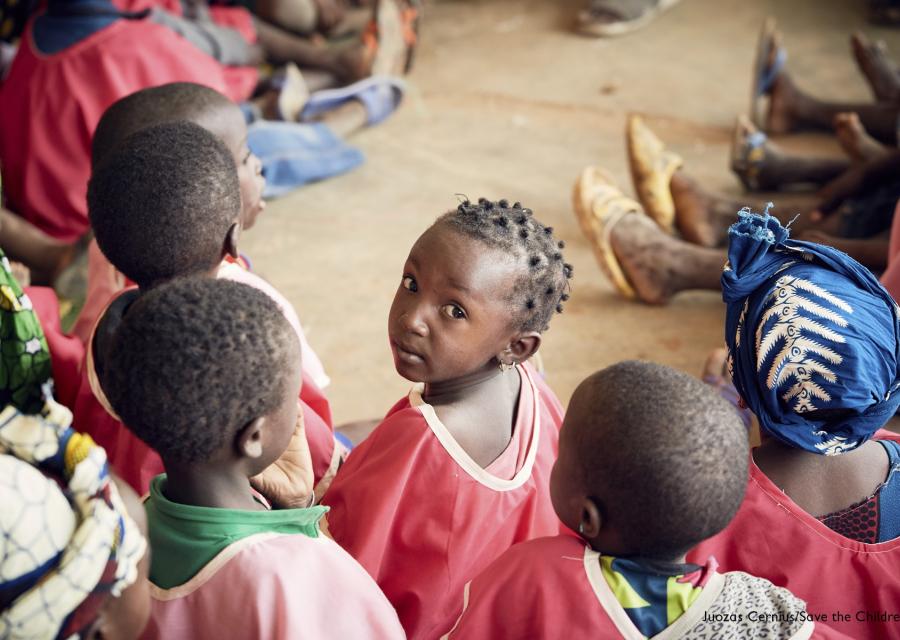 Bambini maliani in cerchio di spalle e al centro una bambina girata guarda in camera