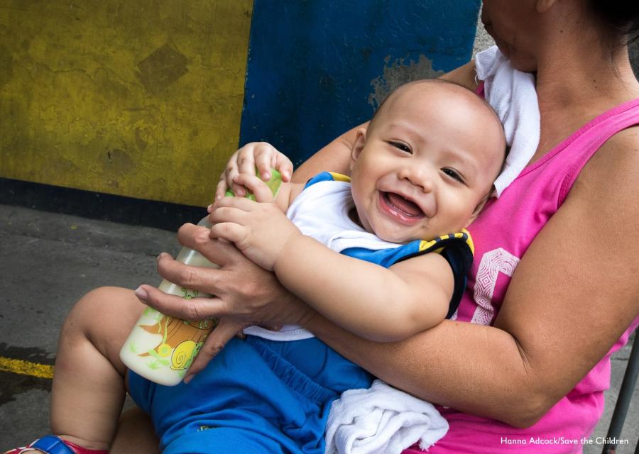 bambino sorridente con biberon e braccia della mamma
