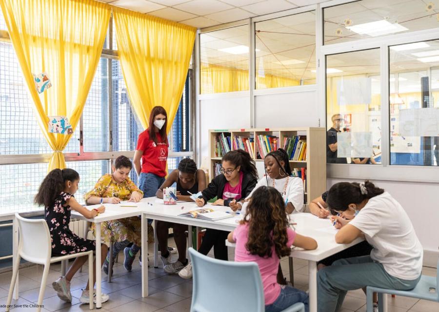 Insegnante con i bambini seduti sui banchi a svolgere attività