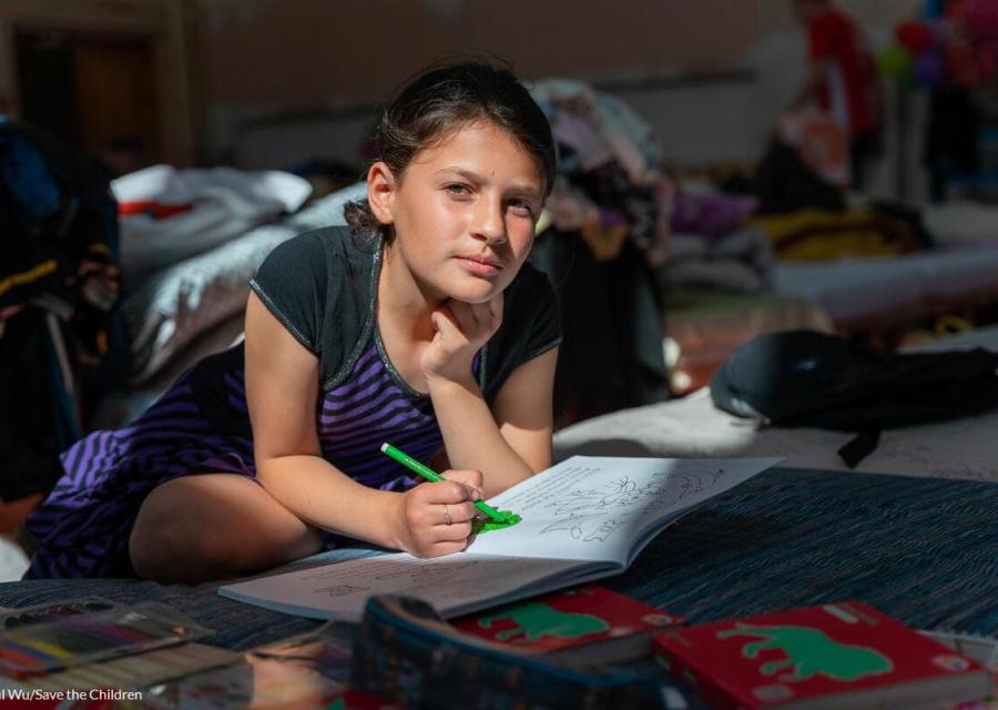 bambina accovacciata su un libro che cerca di studiare in un rifugio in Ucraina