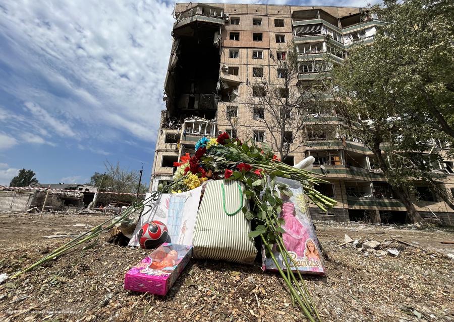 Palazzo distrutto con fiori e bambole in primo piano 