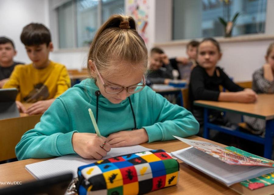 bambina ucraina che scrive su un banco di scuola