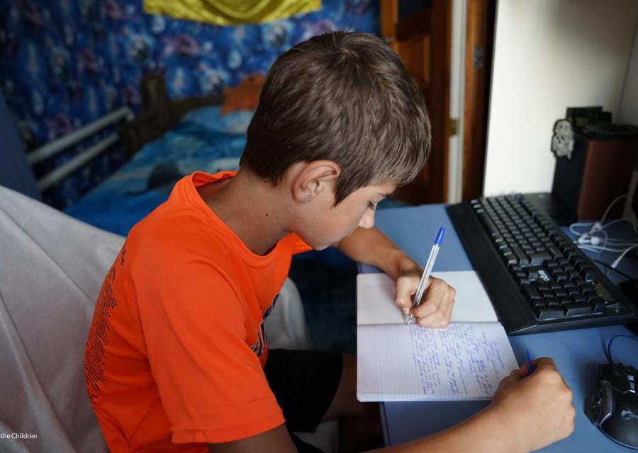 Bambino seduto alla scrivania fa i compiti su un quaderno