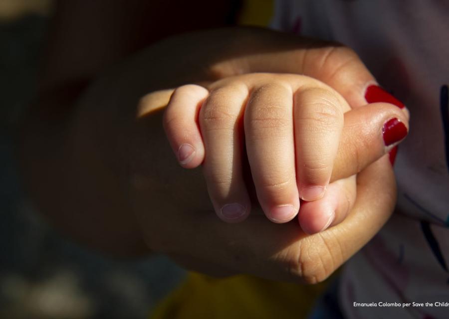 mano di donna con lo smalto rosso tiene la mano di un bambino piccolo