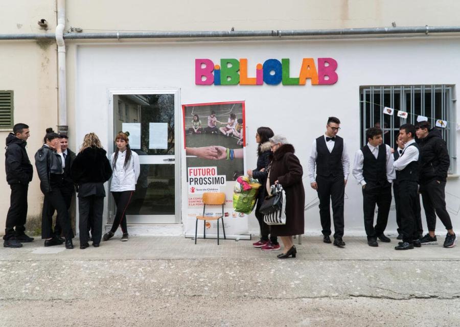 giovani e adulti riuniti di fronte la scuola per un progetto comunitario