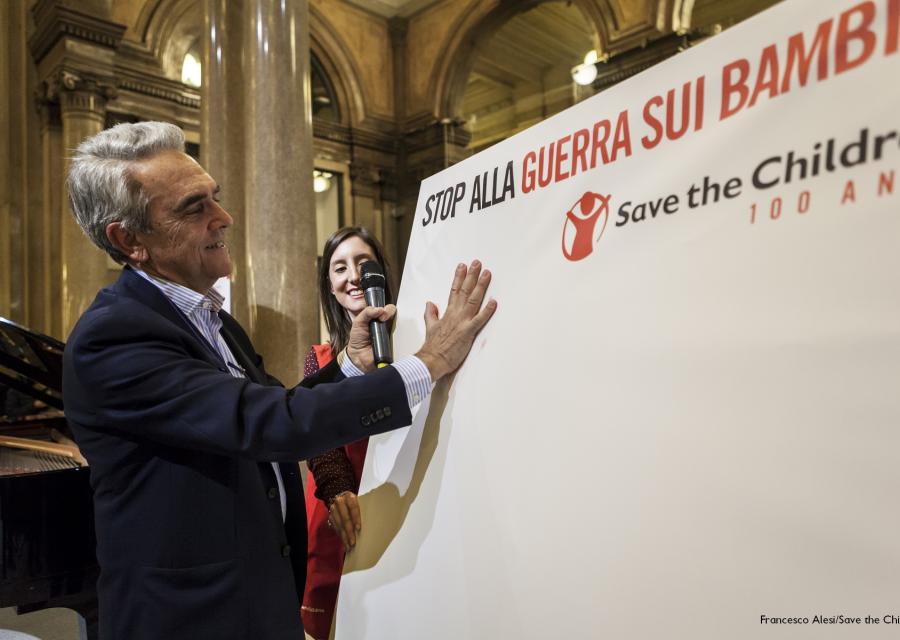 Valerio Neri stampa la sua mano su un cartellone per stop alla guerra sui bambini