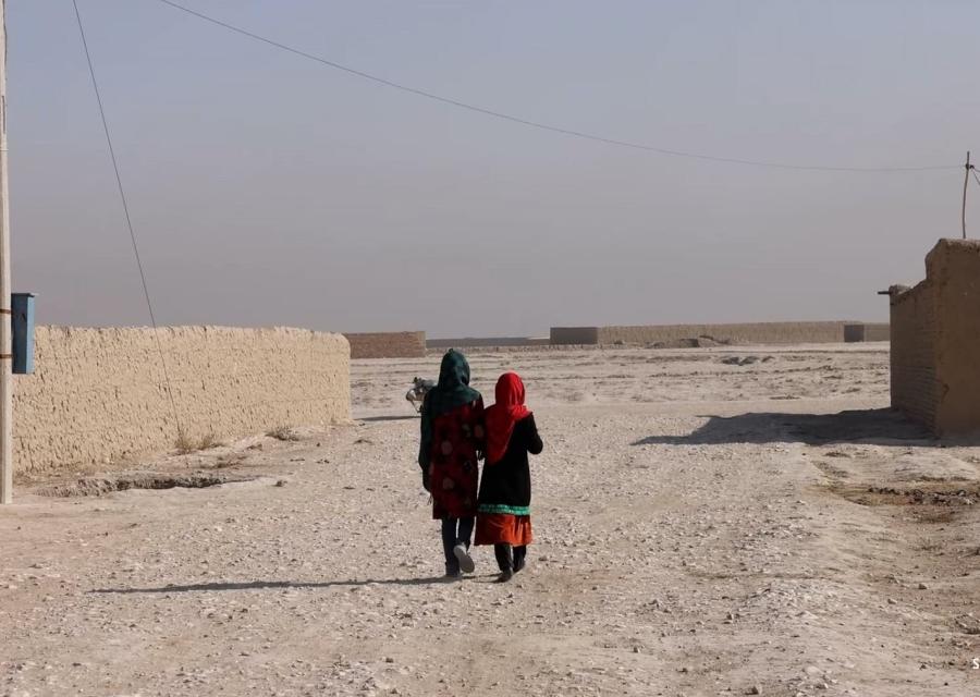 due bambine afghane riprese mentre camminano di spalle in territorio desertico