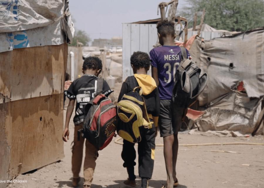 Studenti che camminano in un campo di sfollati in Yemen [Save the Children].