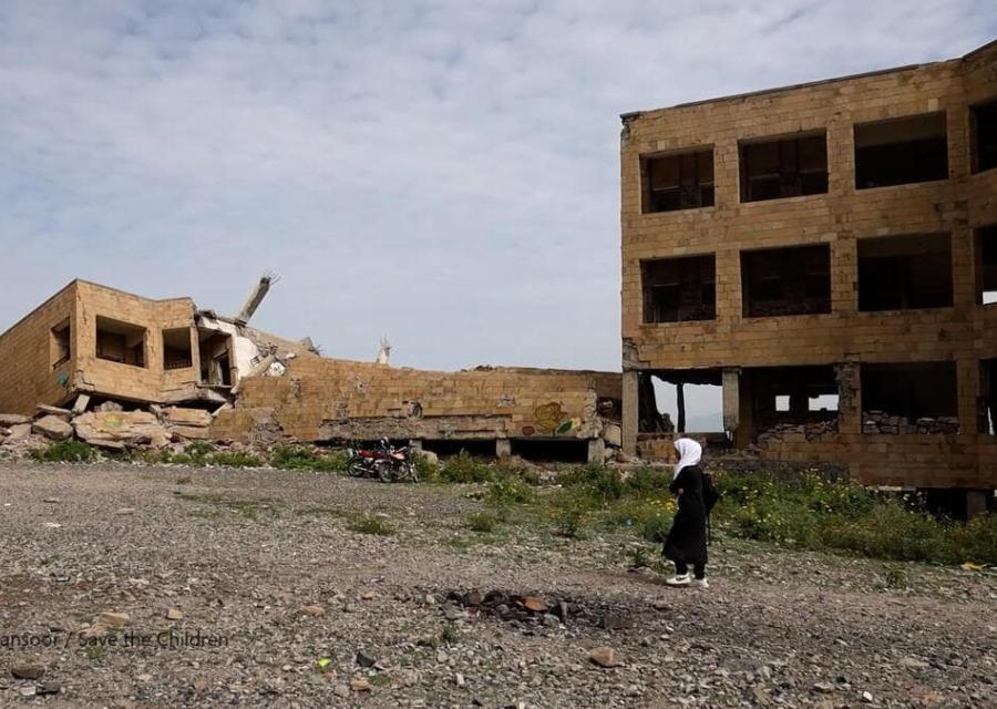 bambina in yemen con alle spalle palazzi distrutti 