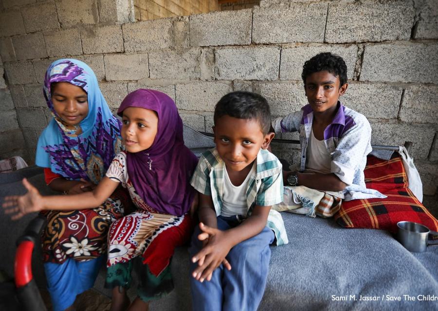 Quattro bambini yemeniti seduti sul letto insieme in una casa di mattoni