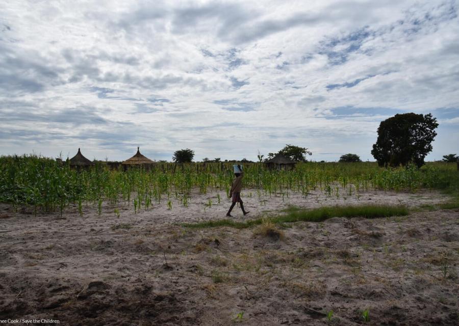 Bambina sorregge un secchio di acqua sulla testa mentre cammina su un terreno in Zambia