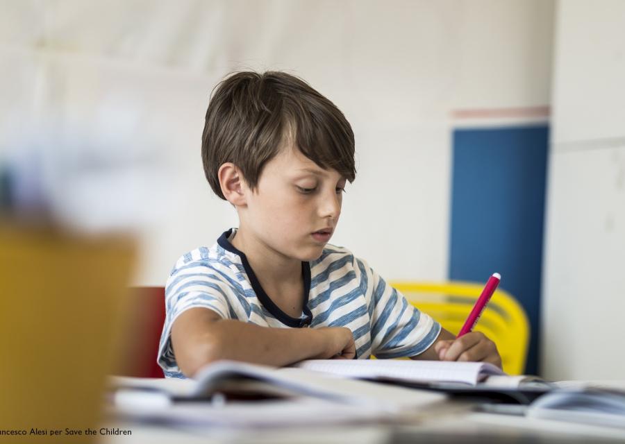 bambino seduto a un banco di scuola che disegna