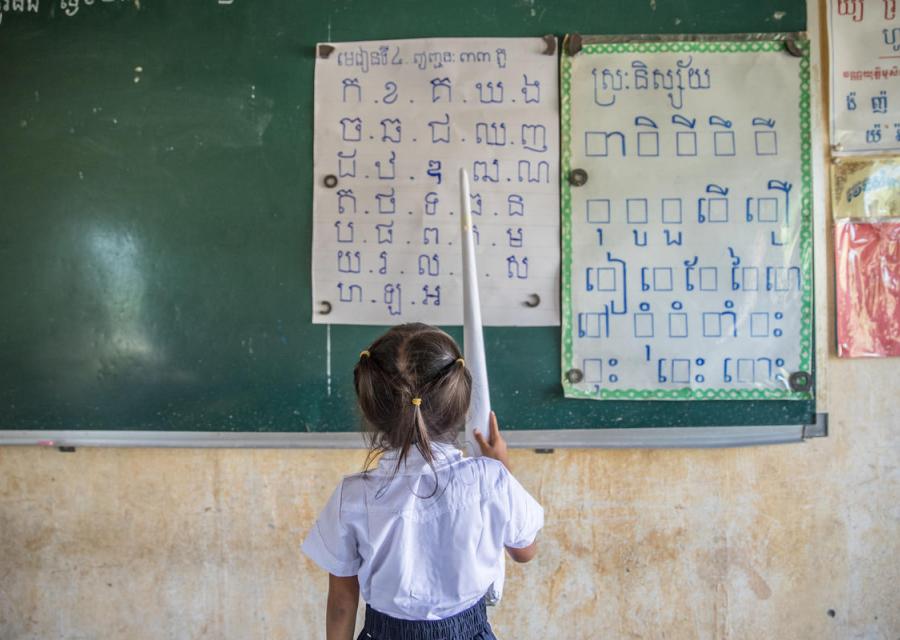 bambina del Vietnam che guarda alcuni cartelli appesi ad una lavagna scolatisca