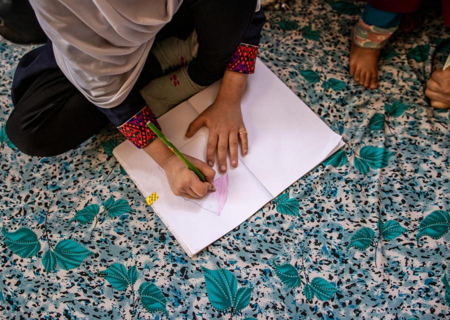 Bambina afgana che scrive su un foglio 