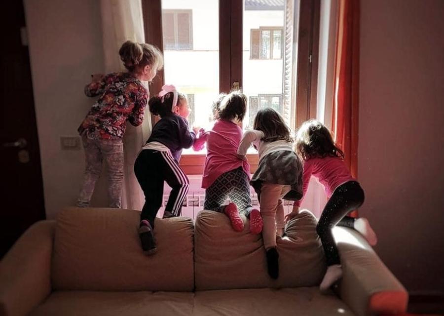 cinque bambine sul divano affacciate alla finestra che guardano fuori