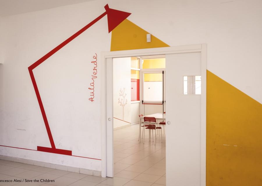 interno di un Punto Luce di Save the Children Italia, muro con disegnata una lampada da tavolo che illumina una porta verso una sala