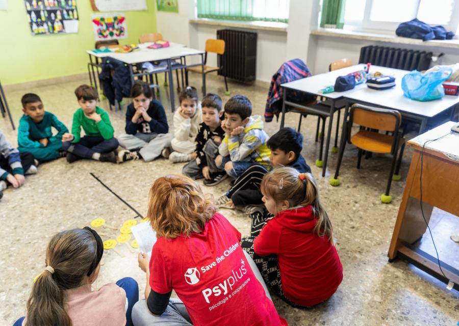 Bambini e bambine seduti a terra in classe in cerchio per lezione inclusiva