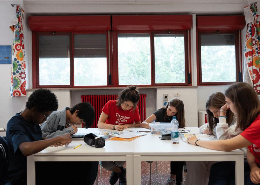 bambini con educatori scrivono intorno ad un tavolo