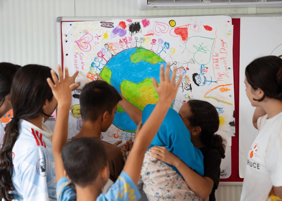 Bambini e bambine di spalle di fronte ad un cartellone per celebrare la giornata dei diritti dell'infanzia