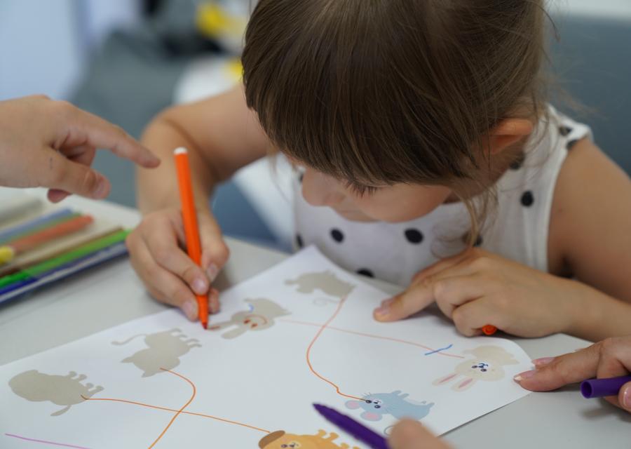 bambina che colora su foglio con pennarelli 