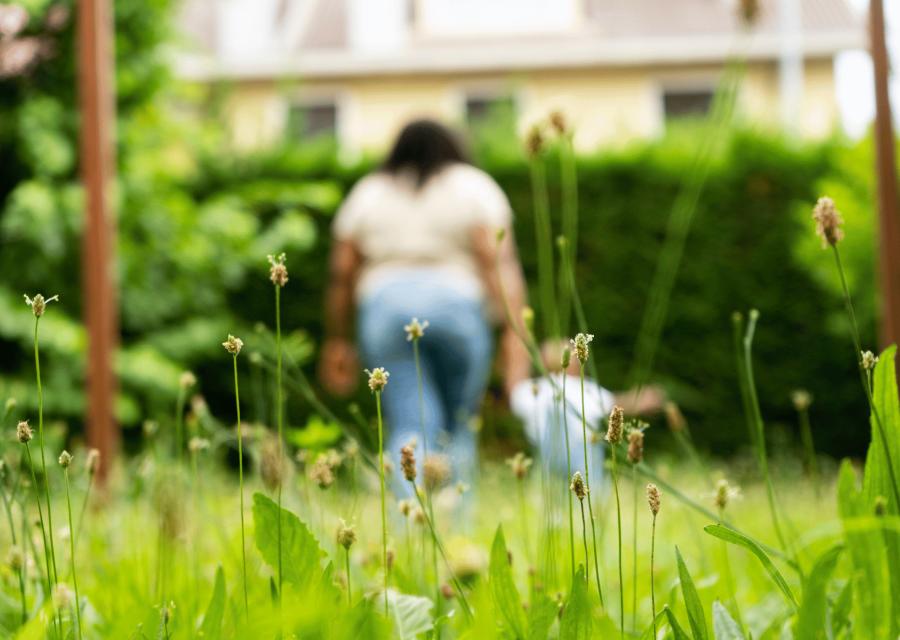 Donna e bambina di spalle che camminano mano nella mano su un prato fiorito 