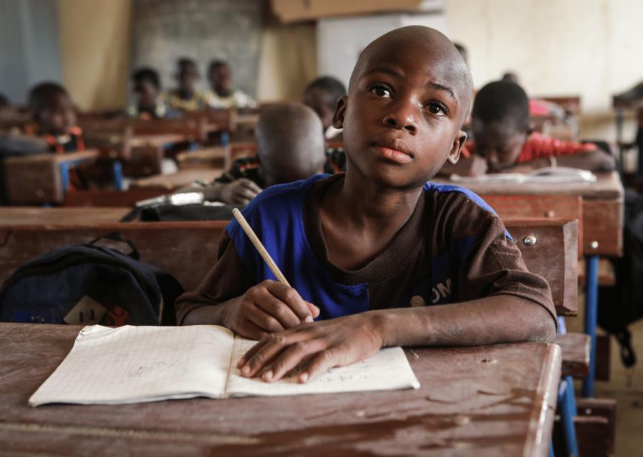 Bambino che  scrive sul banco in un'aula scolastica