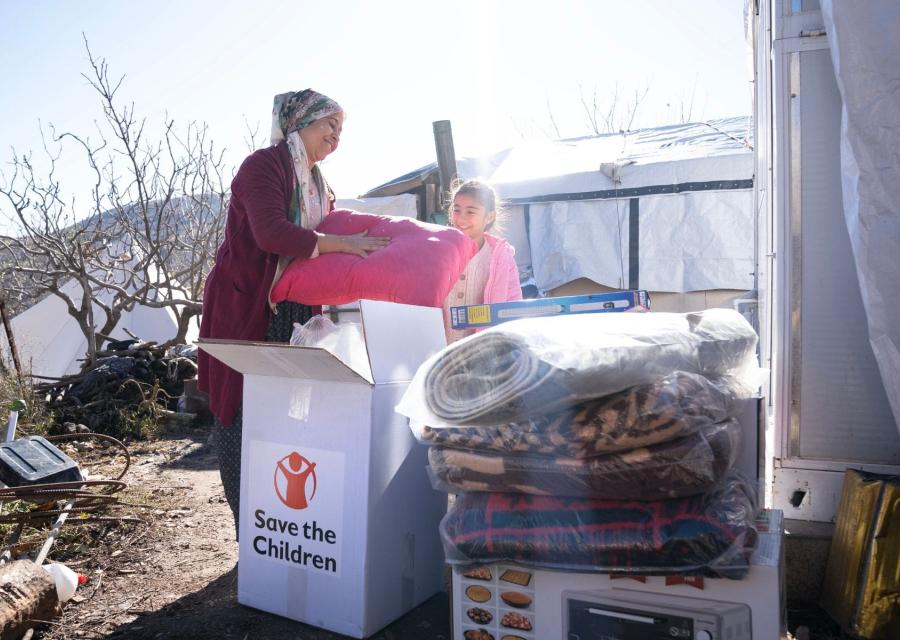 una donna e una bambina sorridono ad oggetti contenuti in una scatola Save the Children